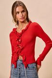 Red ribbed knit cardigan with cascading ruffles, fitted silhouette, denim pairing