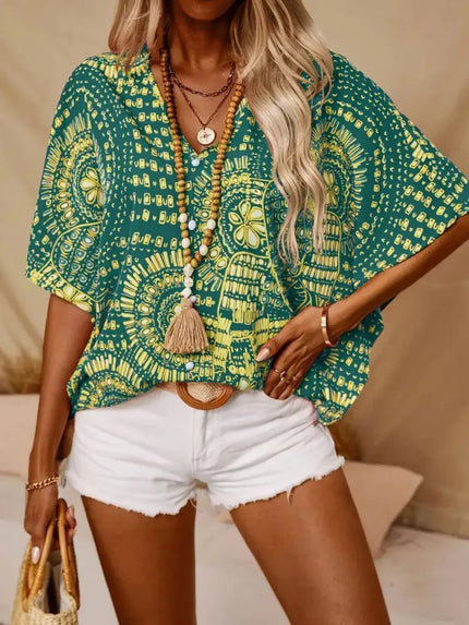 Green and yellow patterned V-neck top with loose fit and beaded necklace accent.