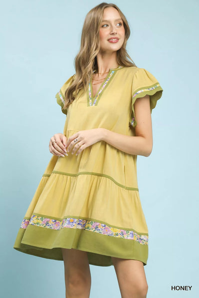 Yellow linen dress with green trim and floral accents, tiered fit, flutter sleeves, V-neckline