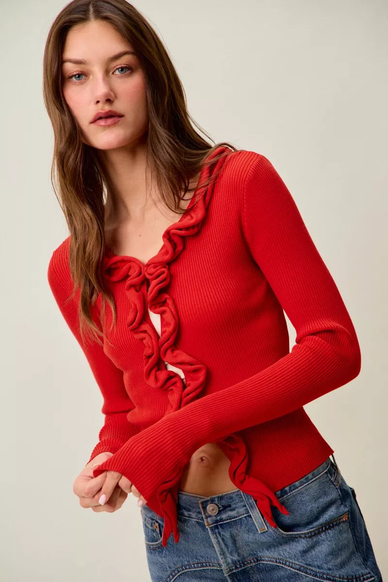 Red ribbed sweater with cascading ruffles, fitted long sleeves, denim pairing.