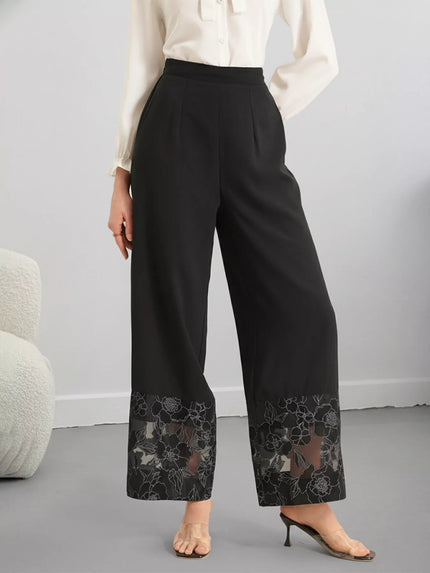 Wide leg pants with floral lace hem detailing on black background