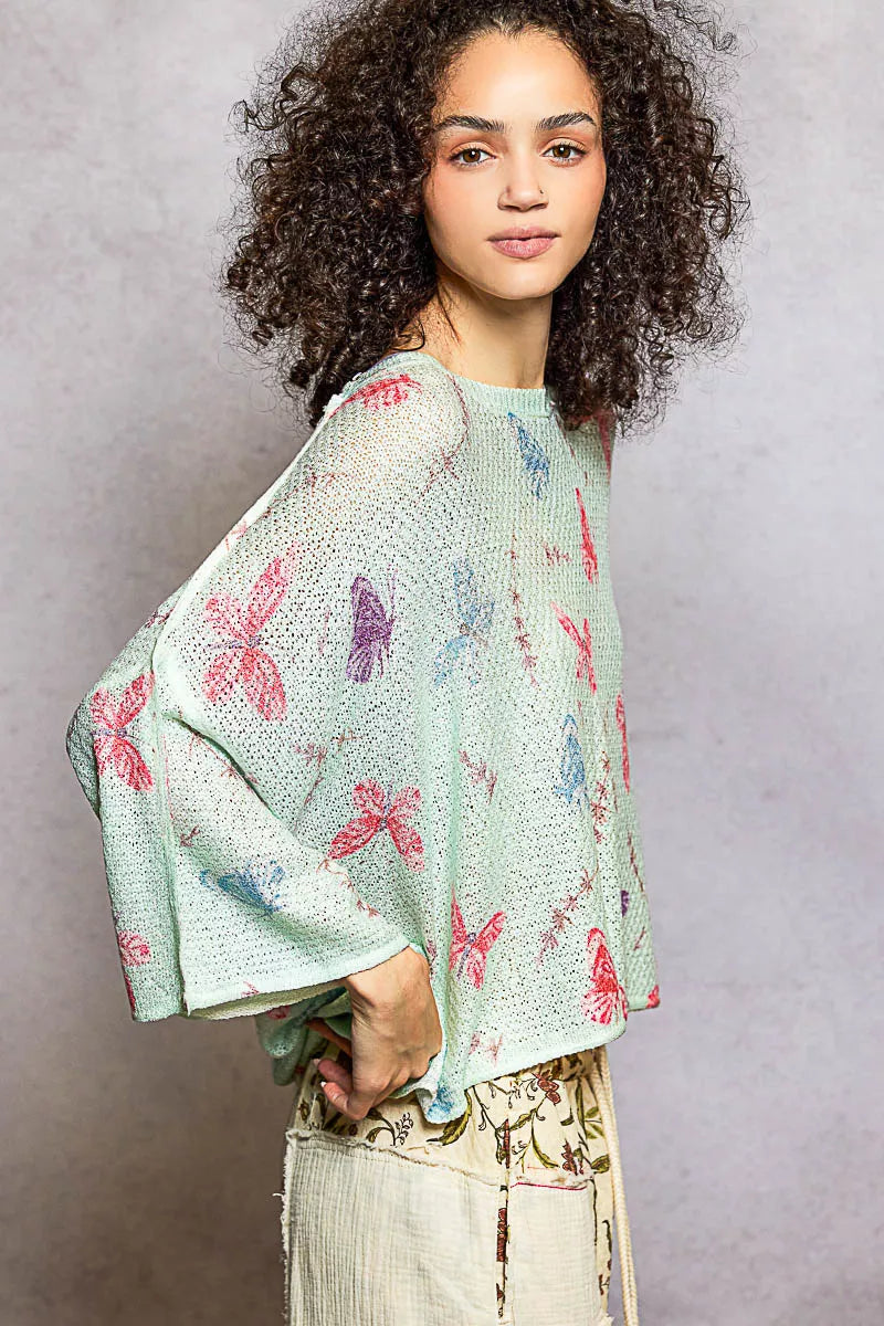Oversized knit top showcasing mint green butterfly pattern and rolled edges