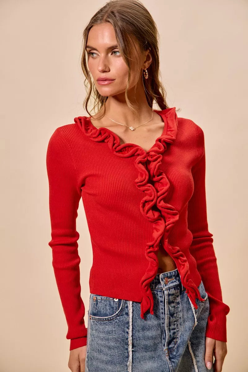 Red ribbed knit cardigan with cascading ruffles, fitted silhouette, denim pairing.