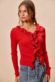 Red ribbed knit cardigan with cascading ruffles, fitted silhouette, denim pairing.