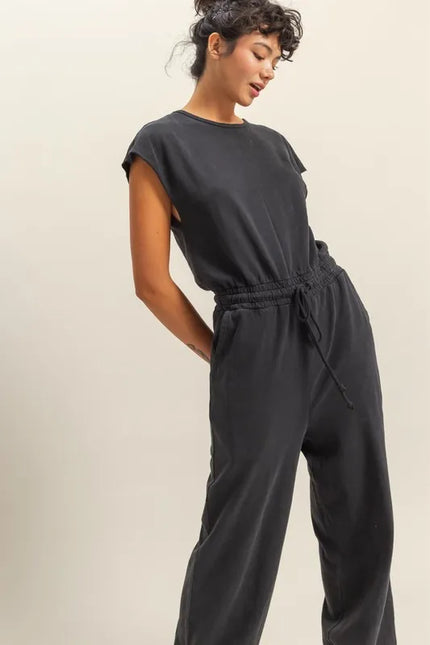Close-up of black jumpsuit drawstring waist and side pockets