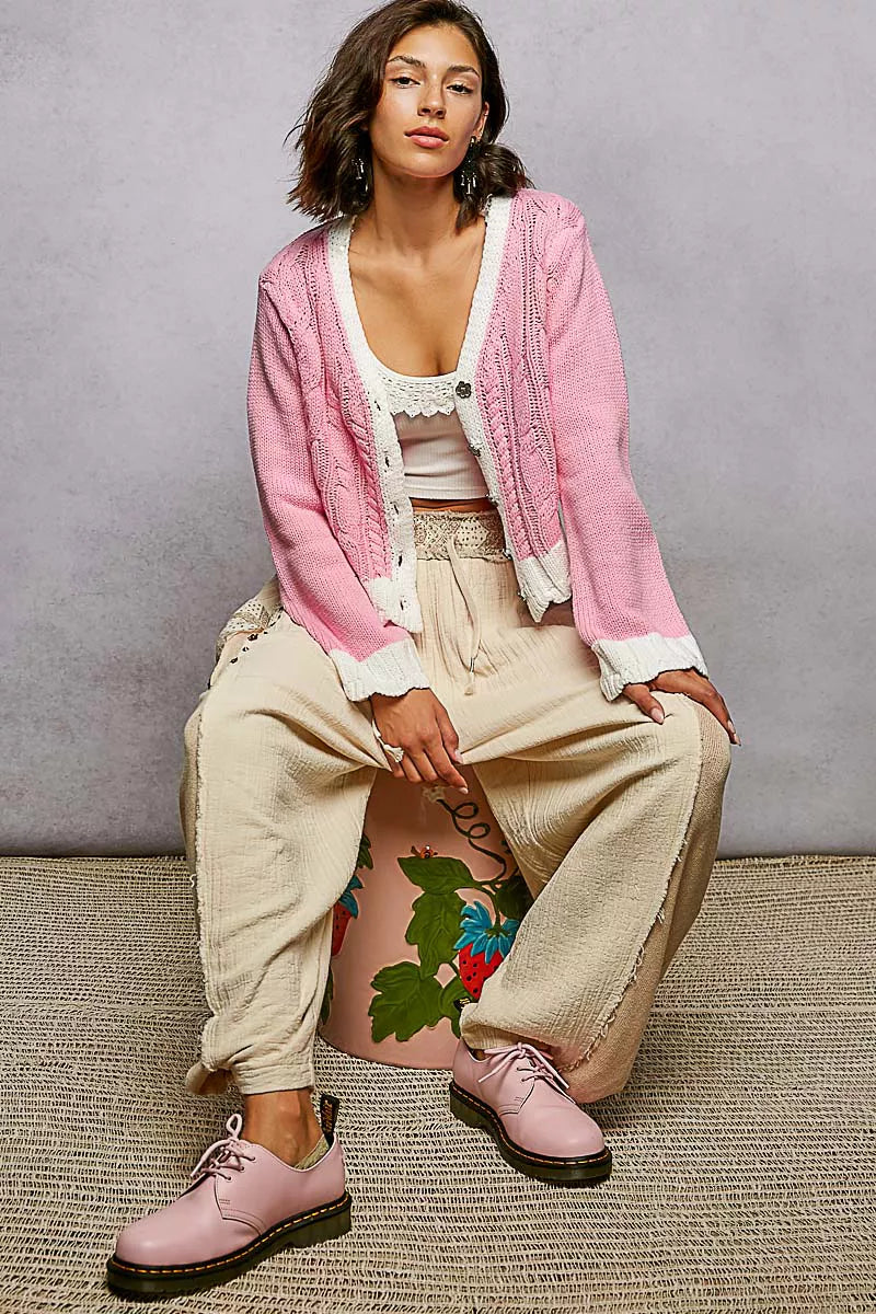 Front view of pink cable-knit cardigan with button closure detail