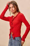 Vibrant red ribbed sweater with cascading ruffles, fitted silhouette, denim pairing.