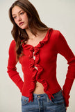 Red ribbed knit cardigan with cascading ruffles, fitted waist, and denim pairing.