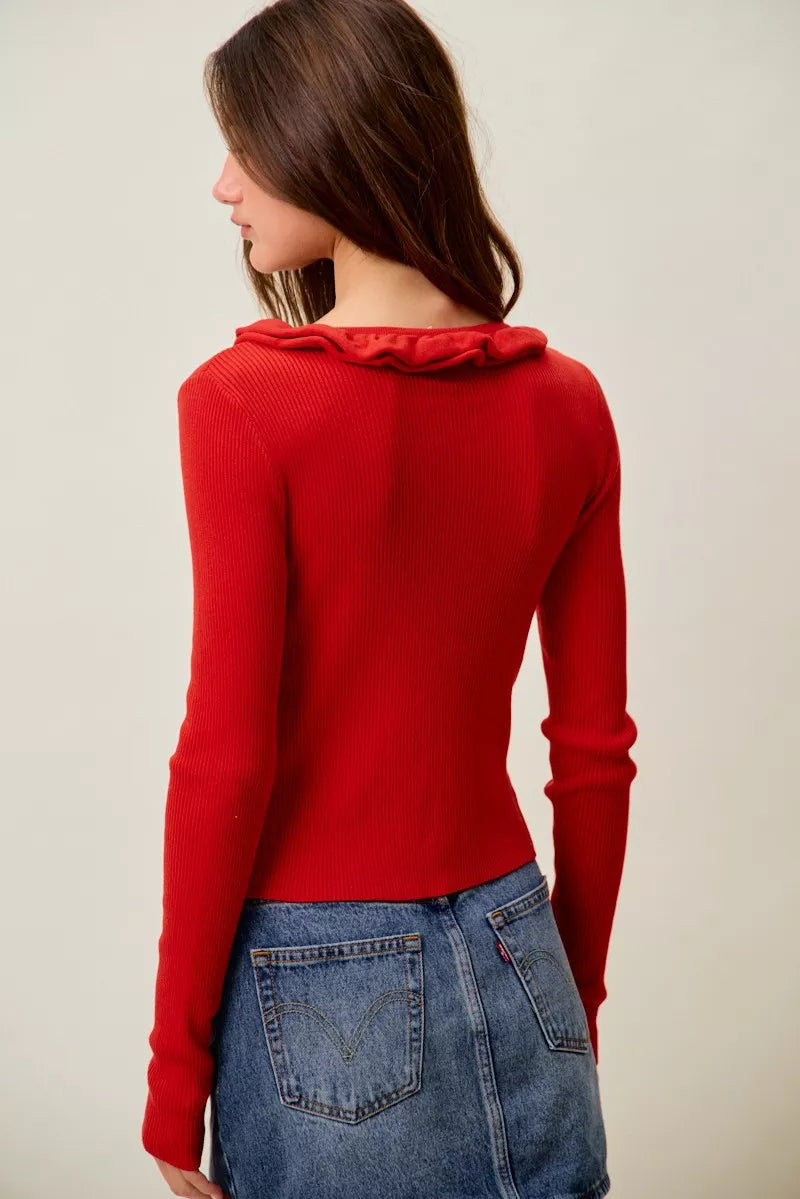 Red ribbed sweater with ruffled neckline and slim fit denim pairing