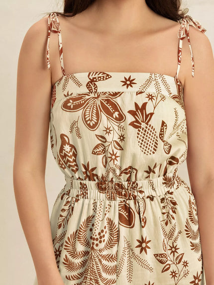 Cream base with brown tropical print, tie straps, smocked waist, wide-leg jumpsuit.