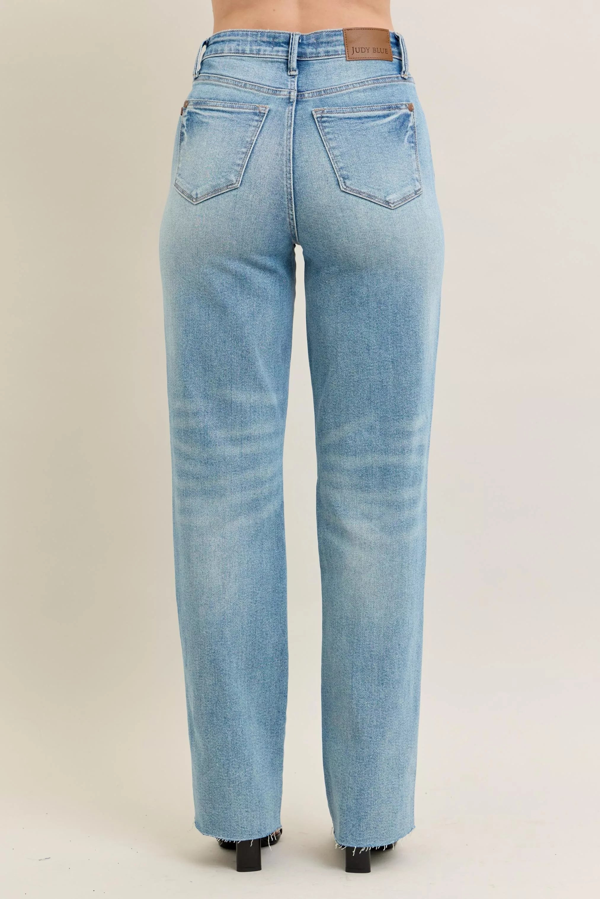 High-waist rigid 90s-style distressed denim jeans, plus fit, mid-wash, structured leg detail.