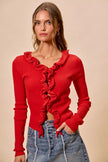 Red ribbed sweater with cascading ruffles, fitted silhouette, denim pairing.