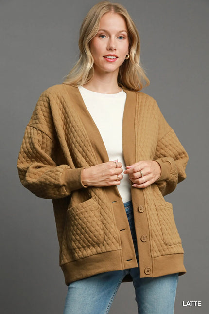 Latte beige Jacquard button-up cardigan with cable knit texture worn over white top
