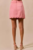 Pink vintage wash denim mini skirt with scalloped hem and back pockets
