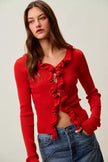 Red ribbed knit cardigan with cascading ruffles, fitted waist, denim pairing.