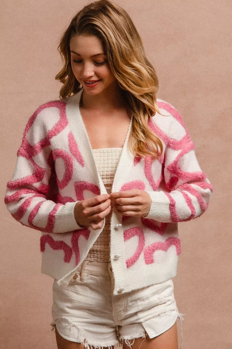 Pink and white textured heart patterned buttoned v neck cardigan with cozy knit fabric.