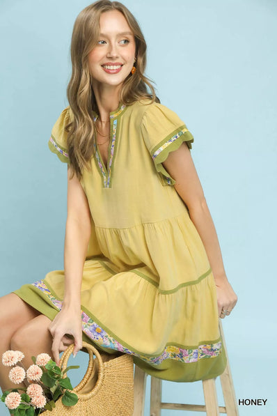Yellow linen tiered dress with floral trim, flutter sleeves, and relaxed fit