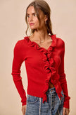Red ribbed knit cardigan with cascading ruffles, fitted silhouette, denim pairing.