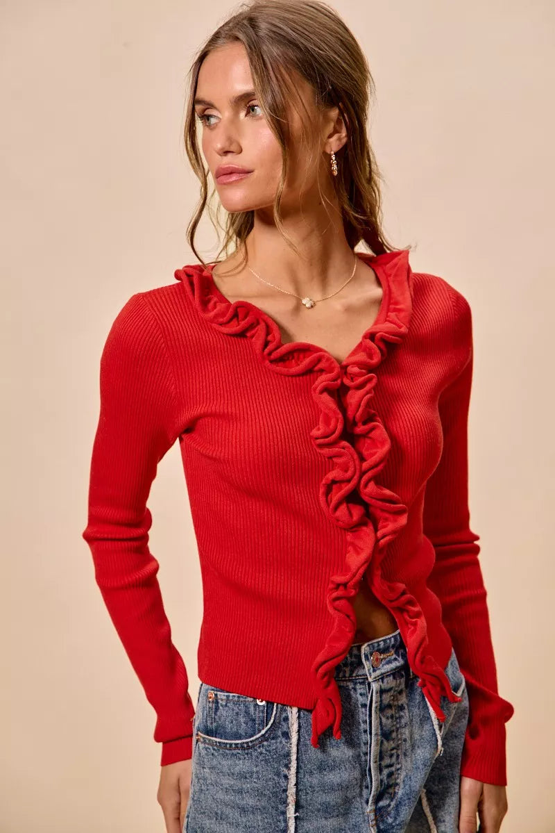 Red ribbed knit cardigan with cascading ruffles, fitted silhouette, denim pairing.
