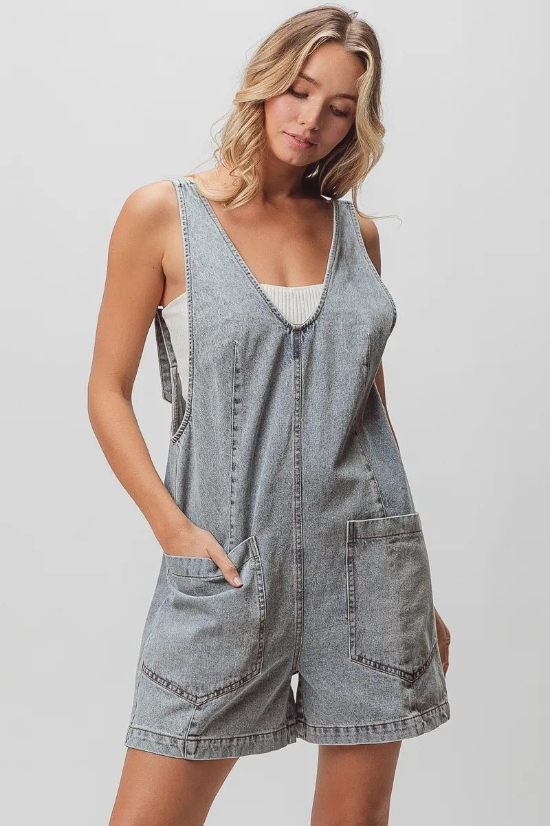Light-washed denim shortall with patch pockets and adjustable straps.