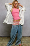 White openwork cardigan with scalloped edge, lightweight knit, loose fit, draped over pink top and jeans
