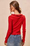 Red ribbed knit sweater with ruffle neckline and fitted silhouette.