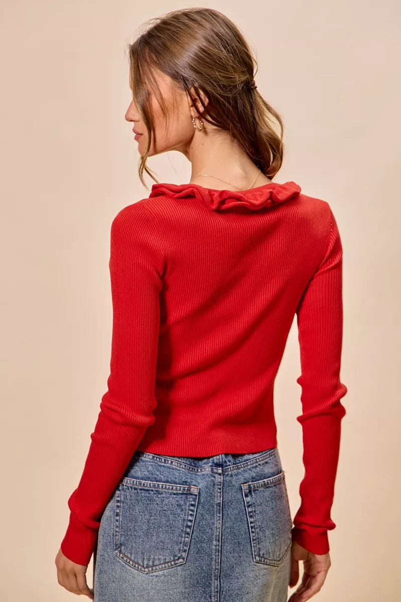 Red ribbed knit sweater with ruffle neckline and fitted silhouette.