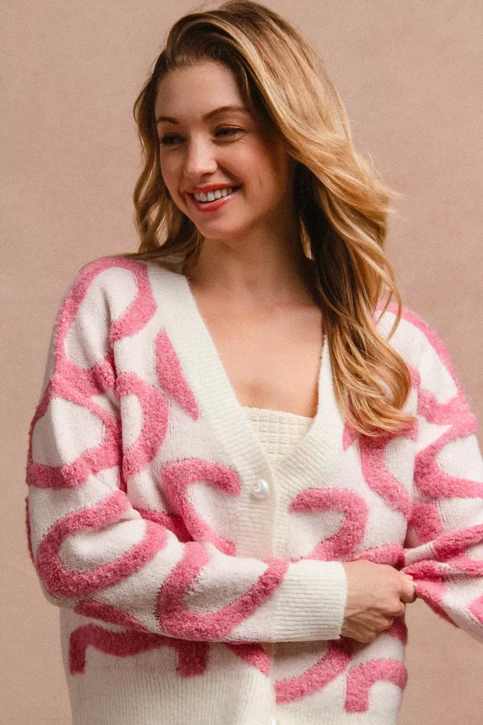 Pink and cream textured heart patterned buttoned v neck cardigan with cozy knit fabric.