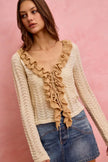 Cream pointelle knit cardigan with ruffled tie-front detail and fitted silhouette.