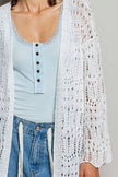 White openwork cardigan with scalloped edge, light blue ribbed top, denim jeans