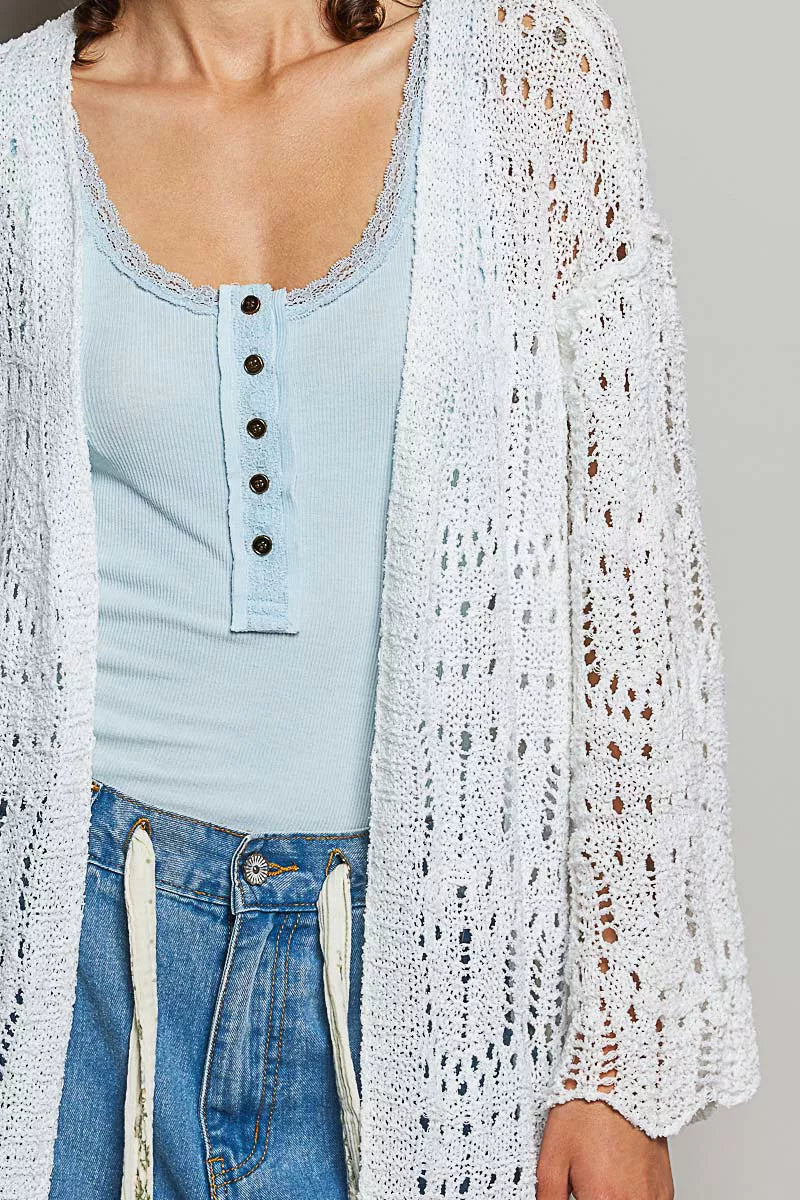 White openwork cardigan with scalloped edge, light blue ribbed top, denim jeans