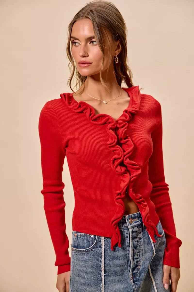 Vibrant red ribbed knit cardigan with cascading ruffles, fitted silhouette, denim pairing.