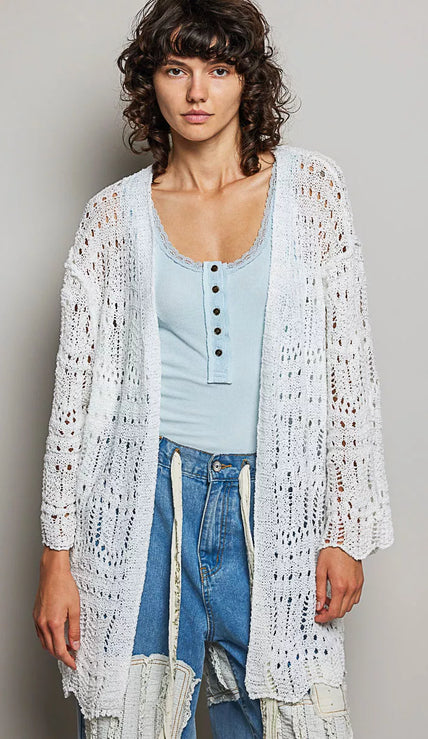 White openwork cardigan with scalloped edge, lightweight knit, loose fit over light blue top and distressed jeans.