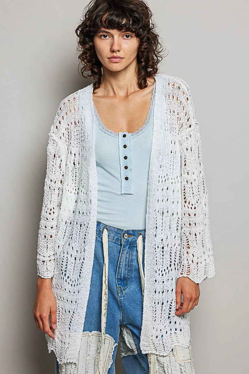 White openwork cardigan with scalloped edge, lightweight knit, loose fit over light blue top and distressed jeans.