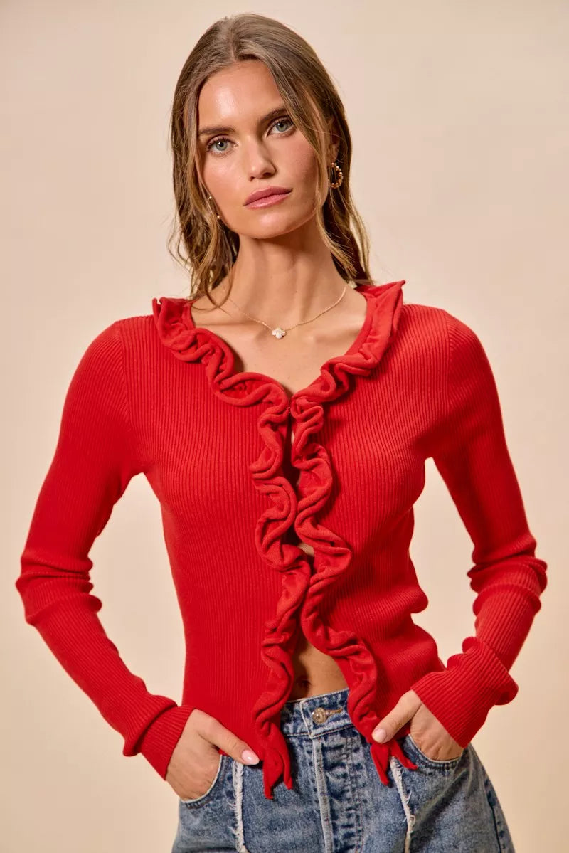 Red ribbed sweater cardigan with cascading ruffles, fitted silhouette, denim pairing.