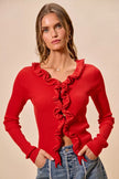Red ribbed sweater cardigan with cascading ruffles, fitted silhouette, denim pairing.