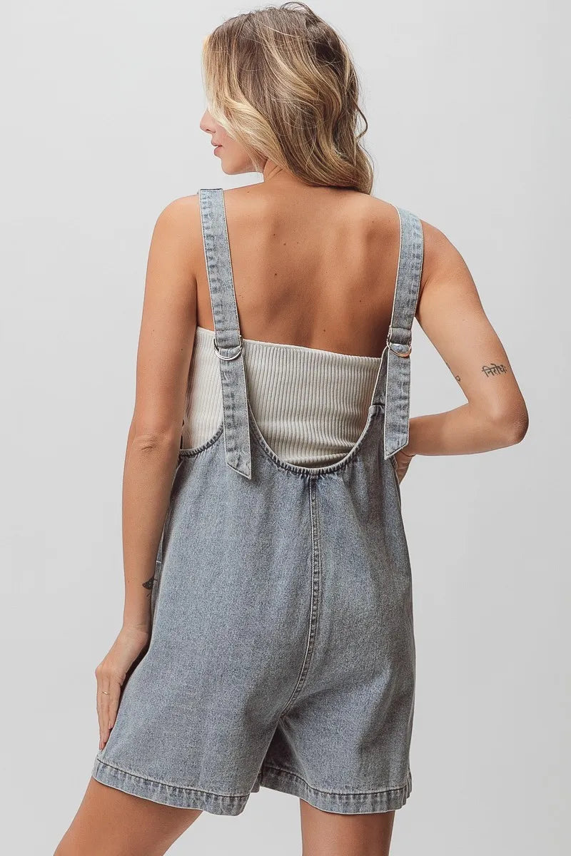 Light-wash denim shortall with ribbed top, open back, and patch detail.